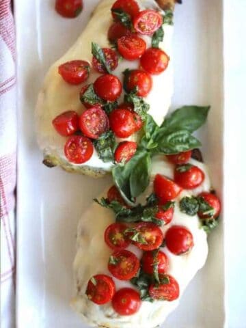 grilled caprese chicken topped with cherry tomatoes and fresh mozzerella