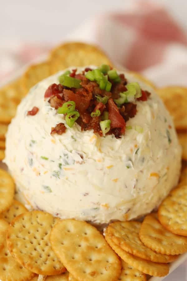 Bacon ranch cheeseball topped with bacon and scallions, surrounded by Ritz Crackers.