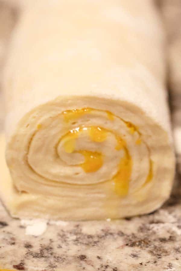 orange sweet rolls rolled up and ready to cut.