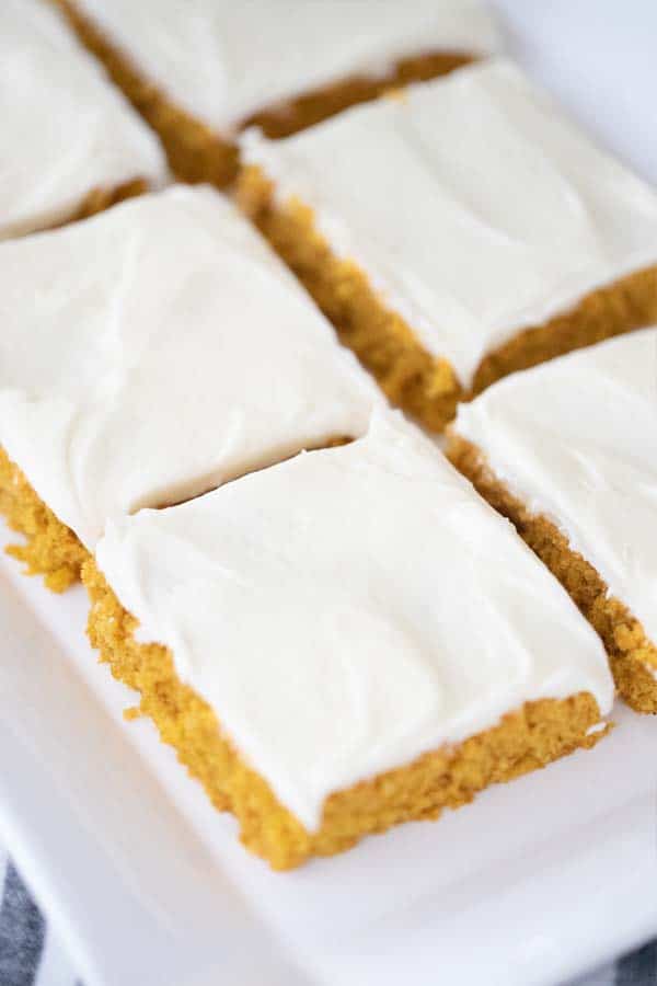 A serving plate with pumpkin squares with cream cheese frosting.