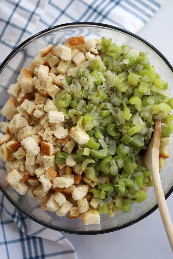 Stuffing filling made with bread cubes, celery, onion and spices in a glass bowl.