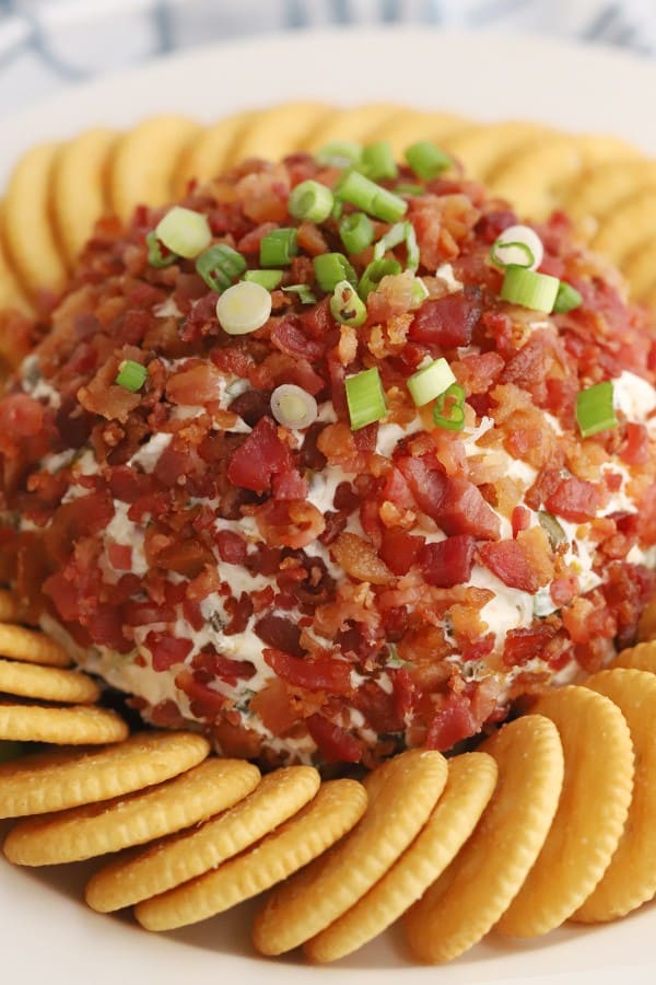 jalapeno bacon cheddar cheese ball topped with scallions and bacon bits, surrounded by Ritz Crackers.