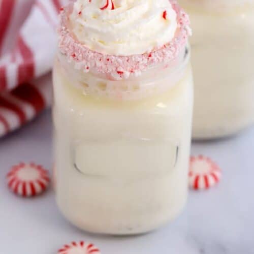 white hot chocolate in a glass mason jar with a peppermint rim.