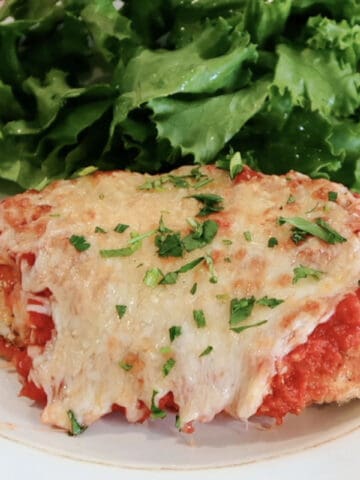 oven baked chicken parmesan on a plate with salad