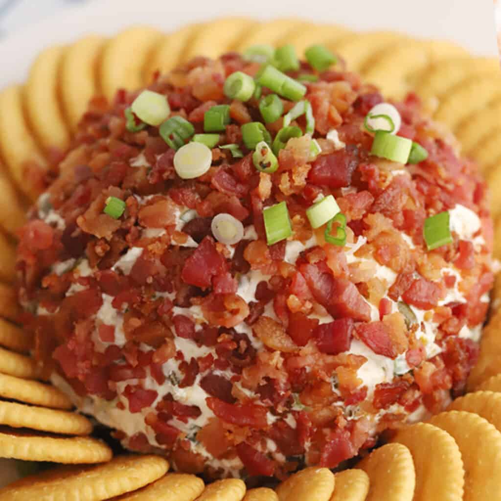 jalapeno bacon cheddar cheese ball topped with scallions and bacon bits, surrounded by Ritz Crackers.