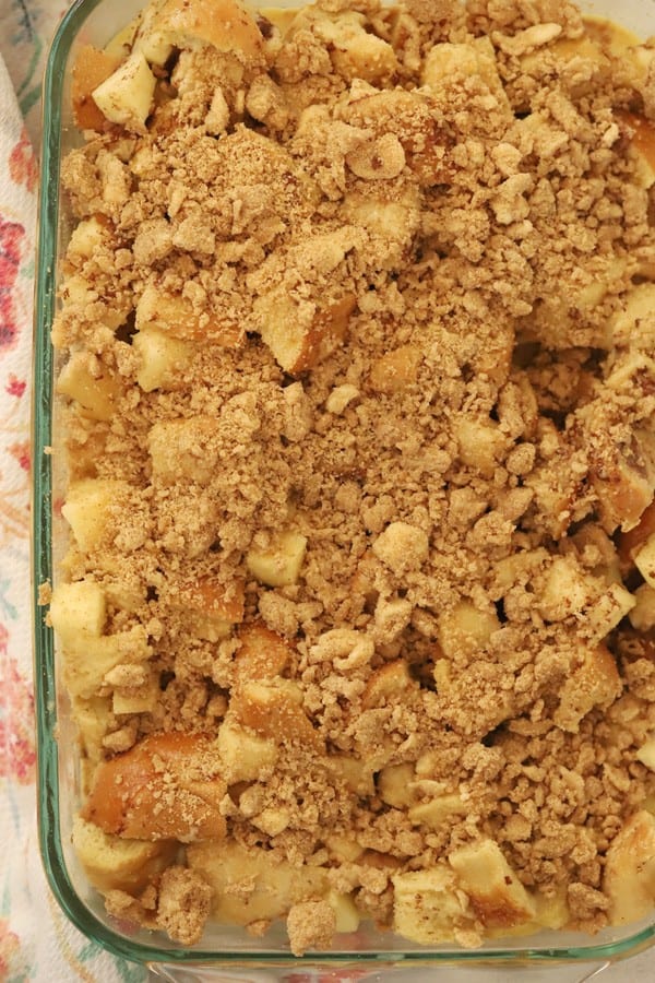 Apple baked french toast in a baking dish topped with streusel and ready to bake.