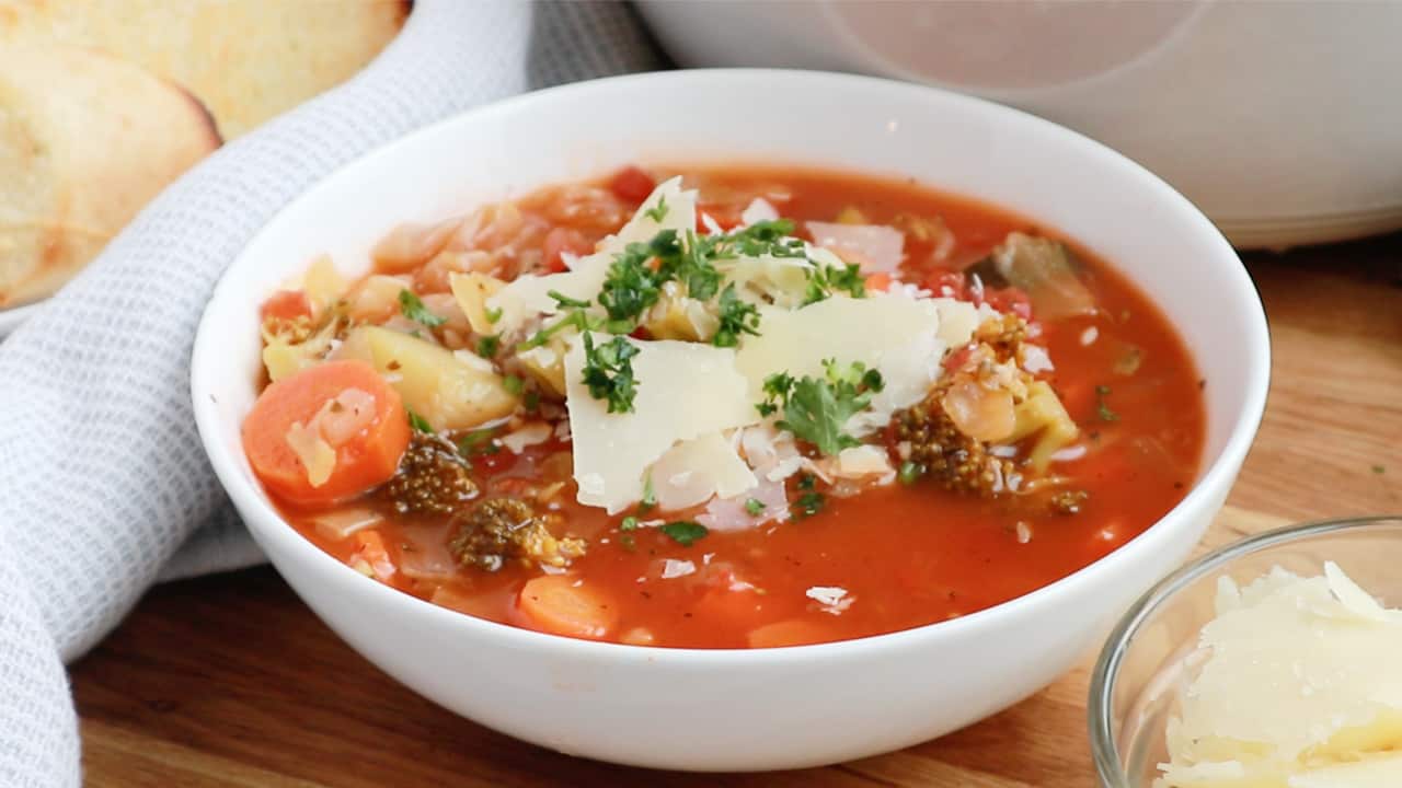 Skinny Vegetable soup in a bowl topped with sour cream and scallions.