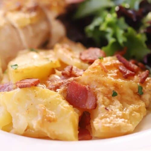 The best scalloped potatoes on a plate with chicken and a green salad