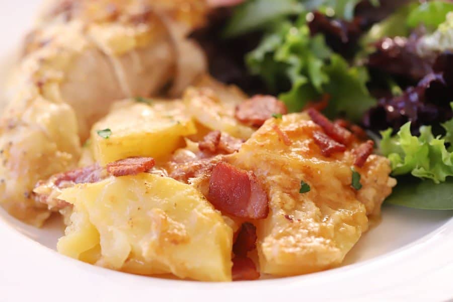 The best scalloped potatoes on a plate with chicken and a green salad