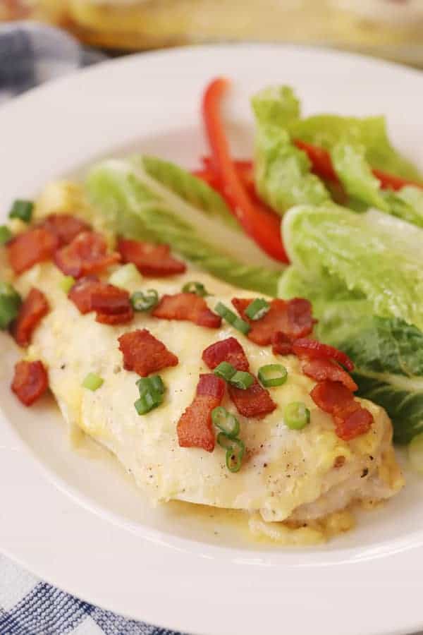 a plate with easy honey mustard chicken topped with bacon bits, sliced green onions, and a side salad. 