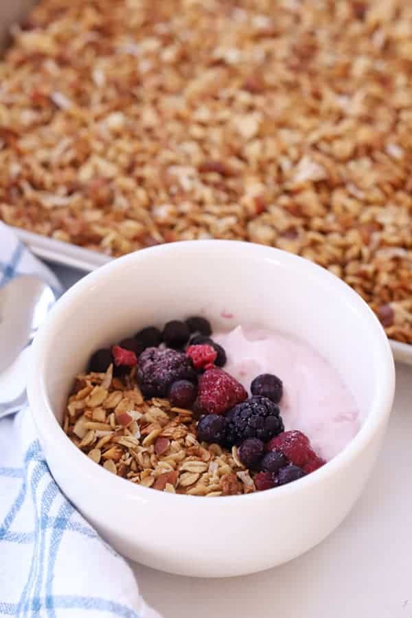 homemade granola with berries and yogurt in a white bowl