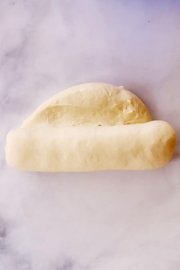 white bread dough being rolled into a loaf shape, ingredients for making bread. best basic white bread recipes, how to make soft bread.