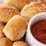 Pretzel bites on a serving dish with a side cup of marinara sauce.