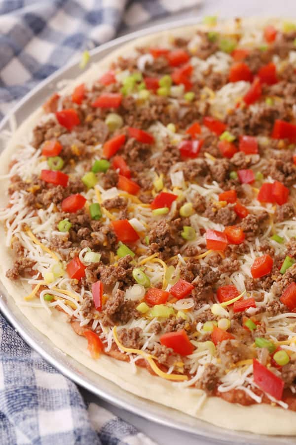 taco pizza recipes covered with toppings and ready to bake, refried bean pizza, mexican pizza sauce. recipe for taco pizza.