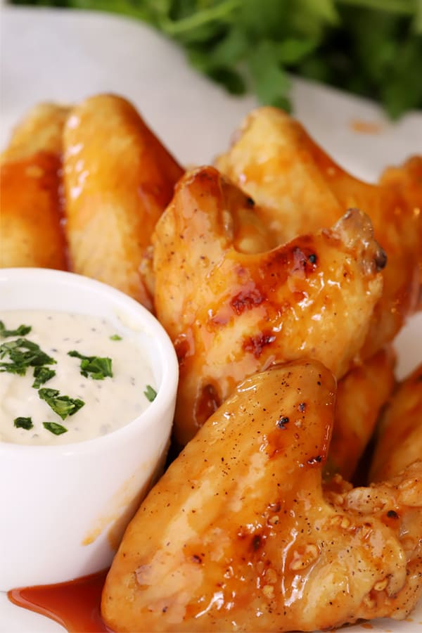 Buffalo chicken wings on a serving platter with a side of dip.