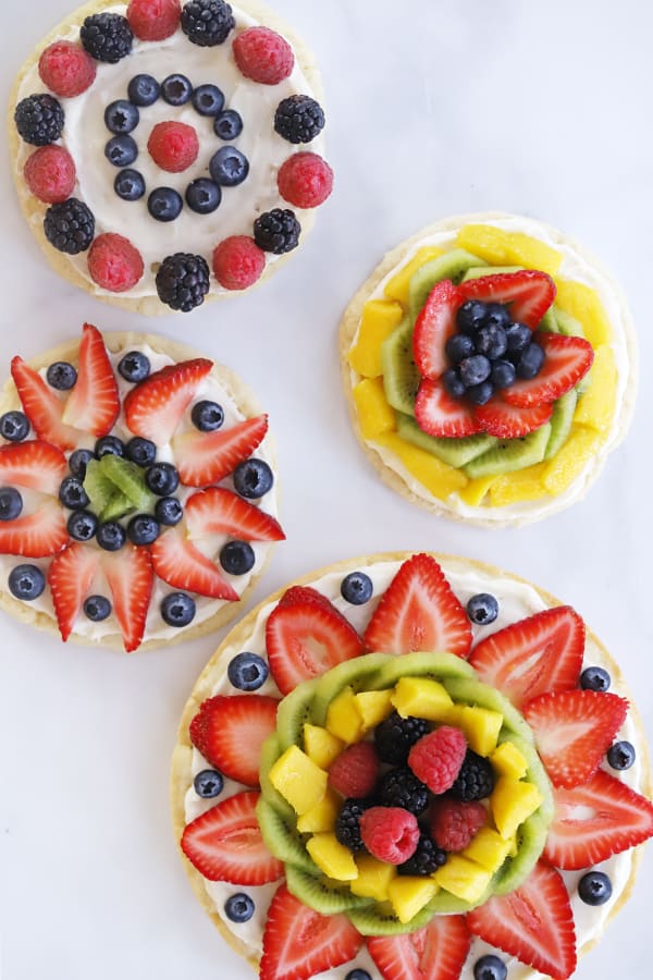 overhead view of four different decorated fruit pizzas