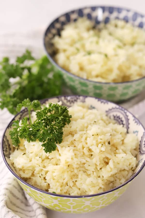 garlic parmesan rice in a bowl garnished with parsley. Garlic rice with parmesan cheese. Rice cooker recipes.