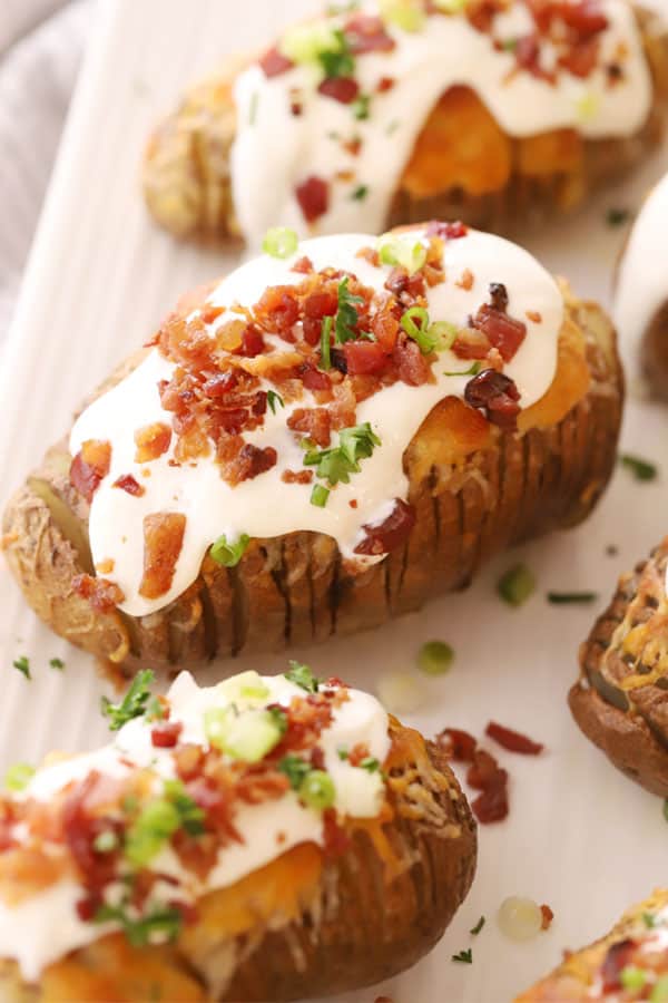 Hasselback Potatoes fully loaded with sour cream, green onions, and bacon bits