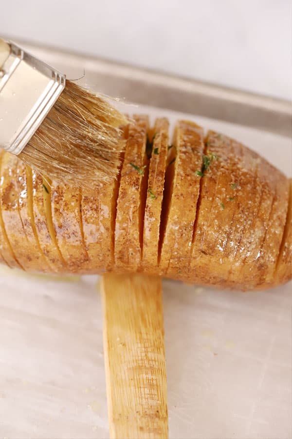 Brushing melted butter and oil over the top of a Hasselback Potato