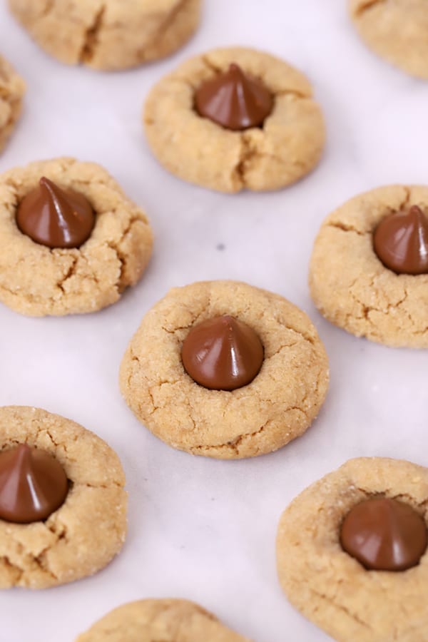 peanut butter blossom cookies on parchment paper, Hershey kiss cookies cooling. 
