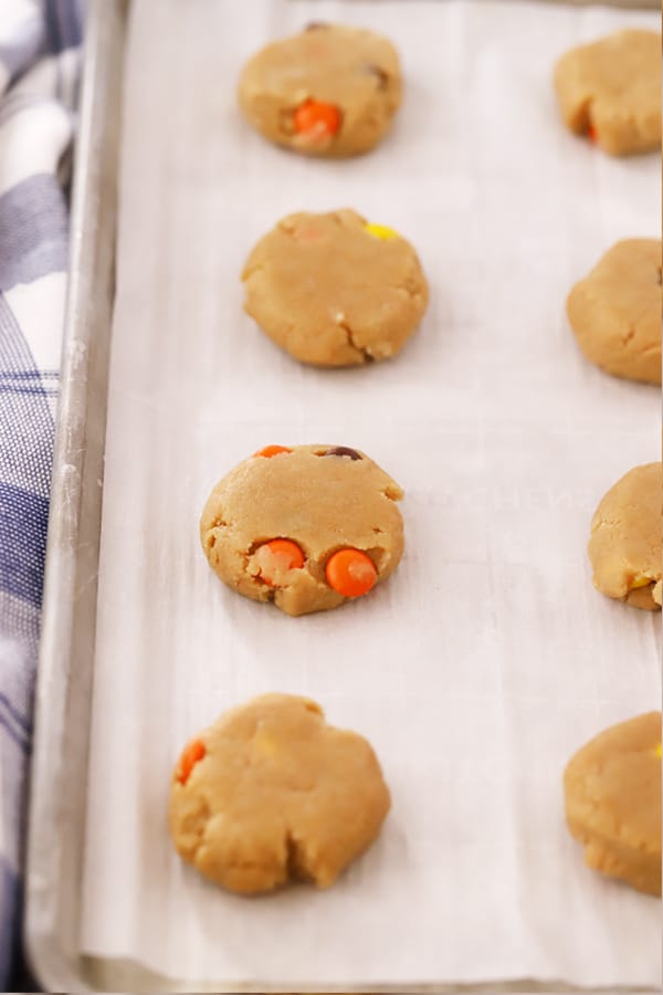 Reese's Pieces cookie dough ready to bake on a parchment lined baking tray.