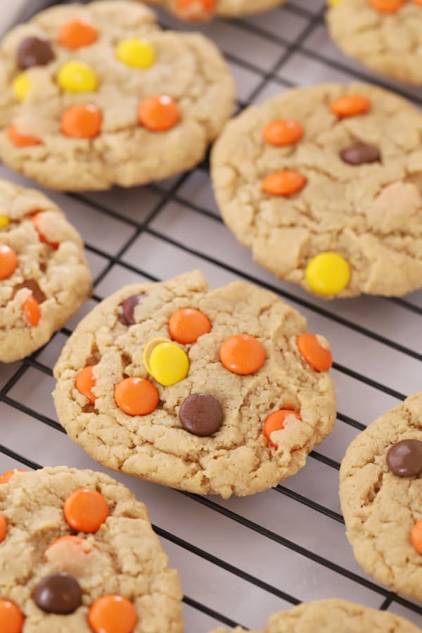 Peanut butter cookies with Reese's Pieces cooling on a wire rack.