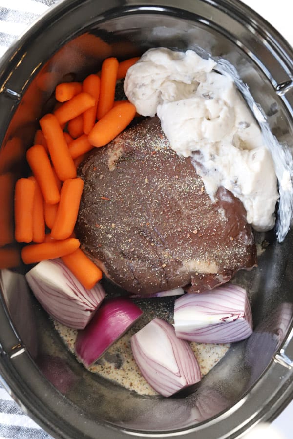 Venison, carrots, onions and mushroom soup in a crock pot ready to cook.