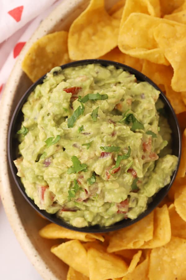 Guacamole in a serving dish with tortilla chips.