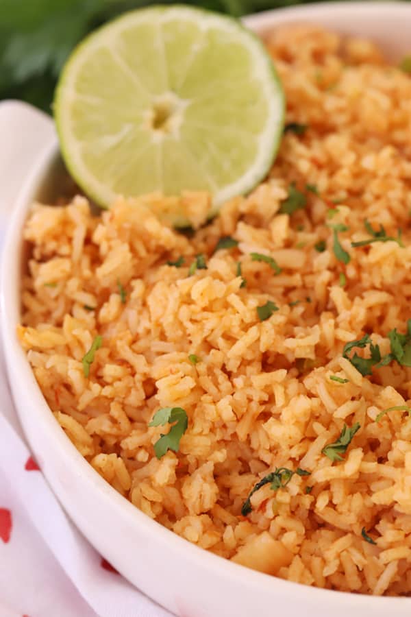 Spanish Rice in a bowl garnished with fresh chopped cilantro and lime.