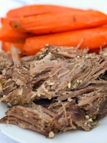 venison roast crock pot with cooked carrots on a plate, deer roast in crock pot.