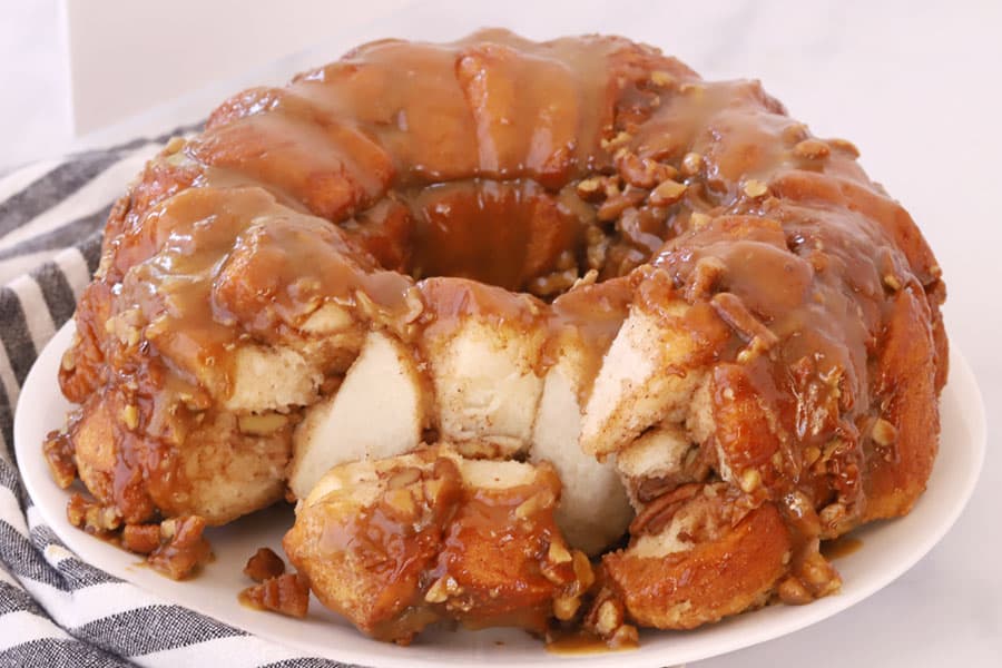 Caramel Pecan Monkey Bread on a white place with a piece removed.