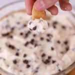 chocolate chip cheesecake dip in a clear bowl, dipping a graham cracker