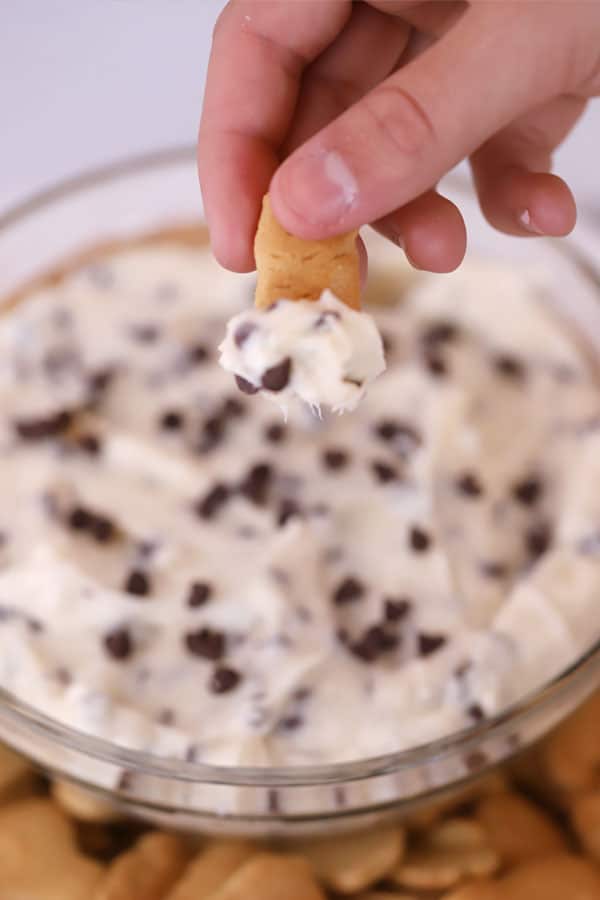 chocolate chip cheesecake dip in a clear bowl, dipping a graham cracker