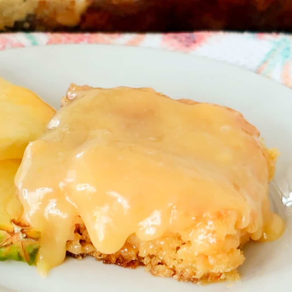 old fashioned pineapple cake on a white plate with a slice of fresh pineapple