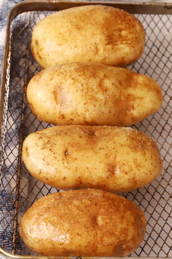 uncooked air fryer baked potatoes recipe in air fryer basket, air fryer baked potato recipe.