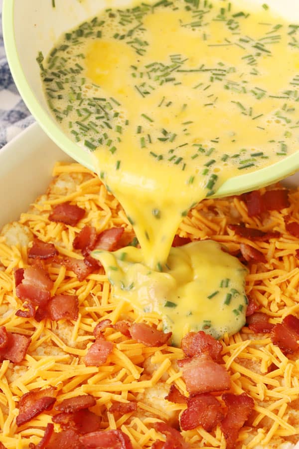 tater tot breakfast casserole recipe, egg mixture being poured over tater tots, how to make breakfast casserole with tater tots.  breakfast casserole bacon, bacon breakfast casserole, egg casserole with tater tots. 
