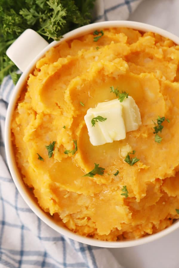 mashed root vegetables in a white bowl with a pat of butter
