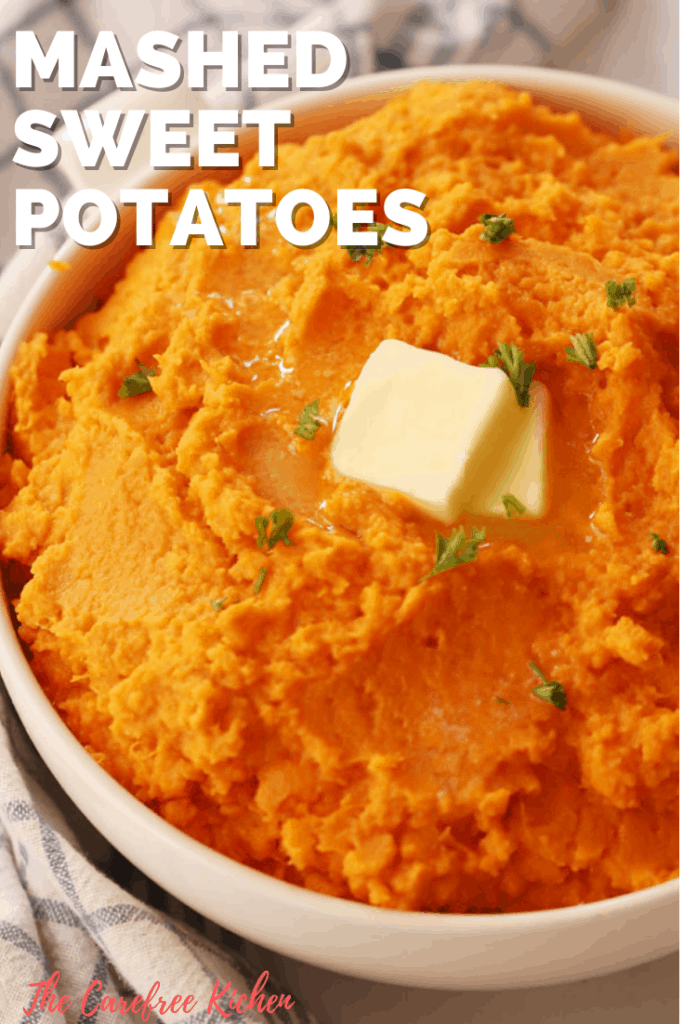 A white bowl full of mashed sweet potatoes topped with a slab of butter.