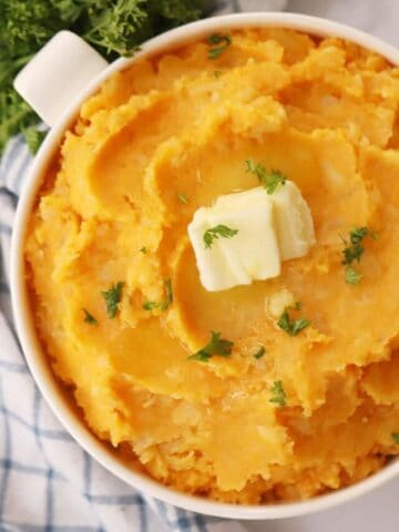 mashed root vegetables in a white bowl with a pat of butter