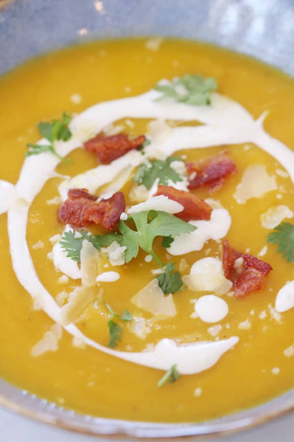 best squash soup recipe in a blue bowl with a creme fresh drizzle on top, recipe for acorn squash soup. 