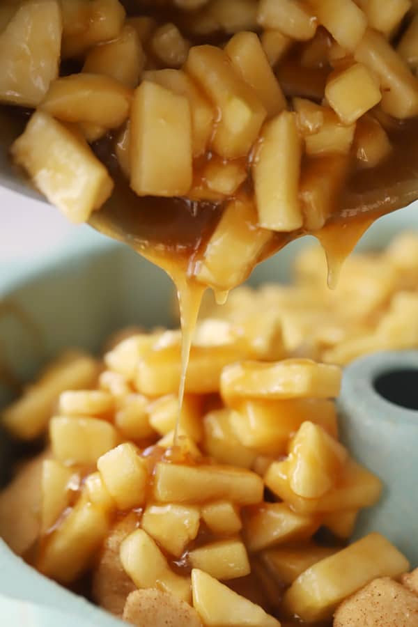 Pouring the apples and caramel sauce over biscuits for apple cinnamon monkey bread, moneky bread, cinnamon apple monkey bread. Apple dessert recipe.