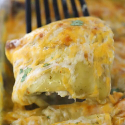 chicken enchilada being scooped out of a baking dish