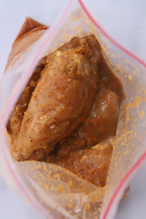 Chicken breasts covered with marinade in a freezer bag.