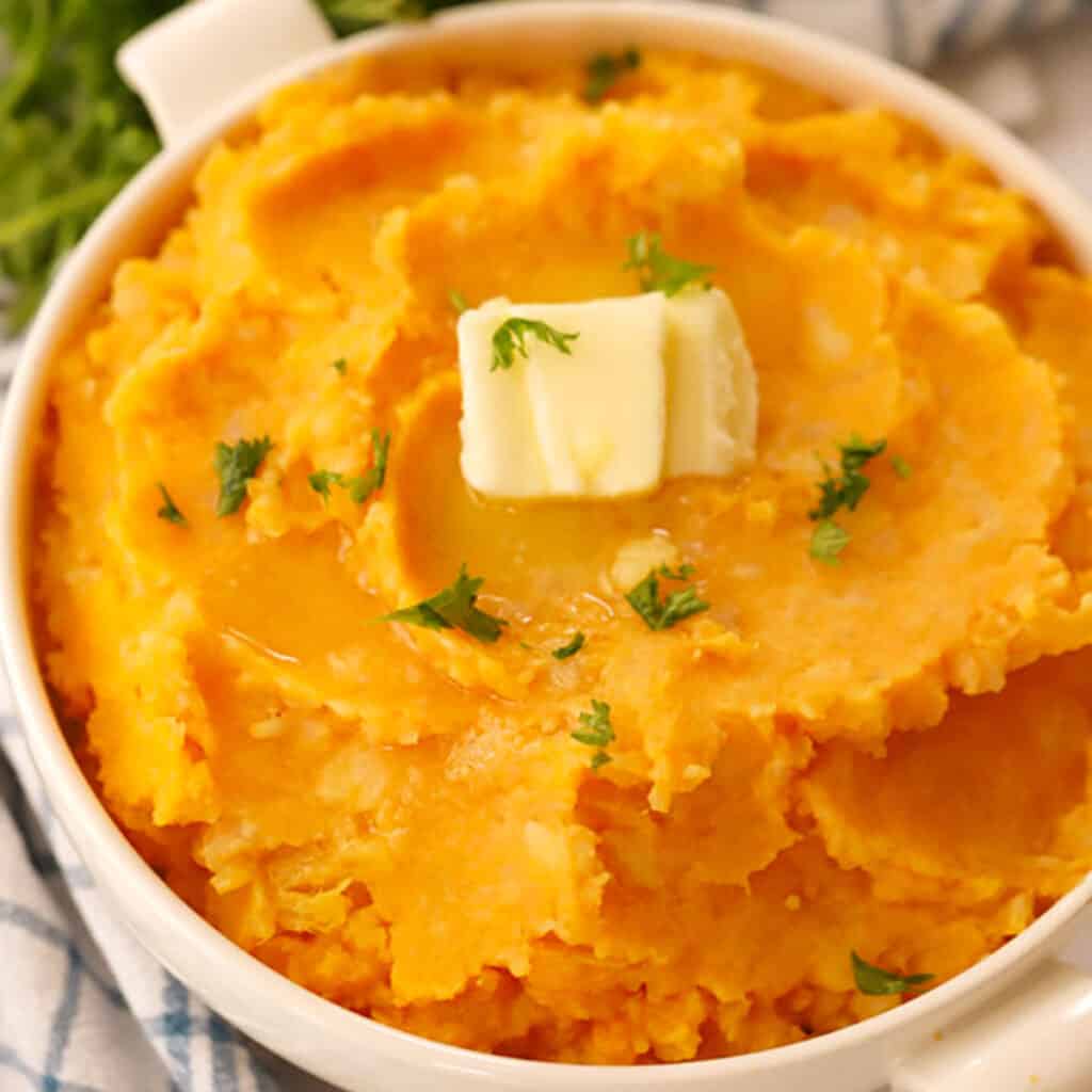 mashed root vegetables in a white bowl with a pat of butter