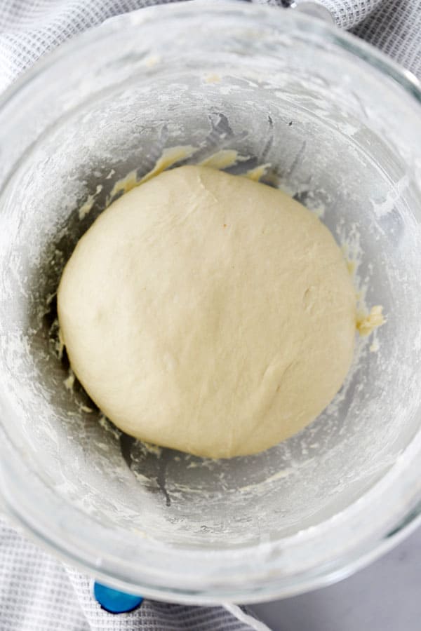 The dough for easy quick rolls in a large glass mixing bowl, showing how to make this easy quick dinner rolls recipe.