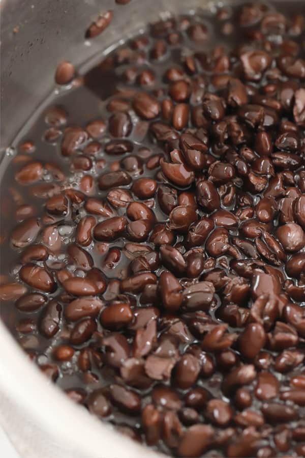 Cooked Black beans in a large pot filled with water. black beans at chipotle. 