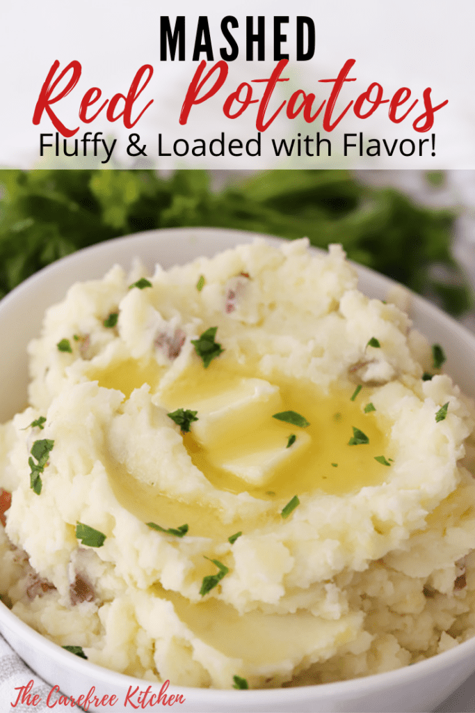 Mashed red potatoes in a bowl topped with herbs and butter.