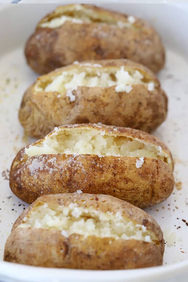 baked potatoes split open on a serving dish.