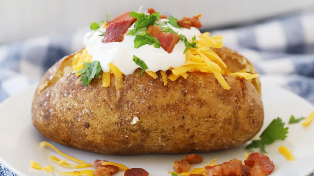 baked potato in oven with toppins, bacon, sour cream, chives, salt and pepper