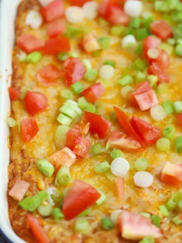 cream cheese bean dip with tomatoes and sliced green onions on top.